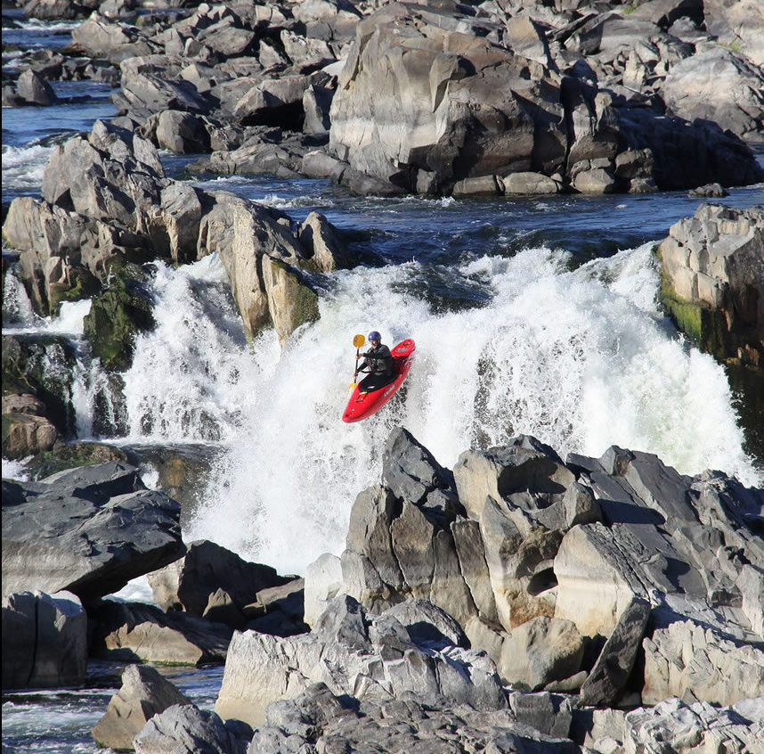 A kayaker descending a waterfall on a Class 6 river.