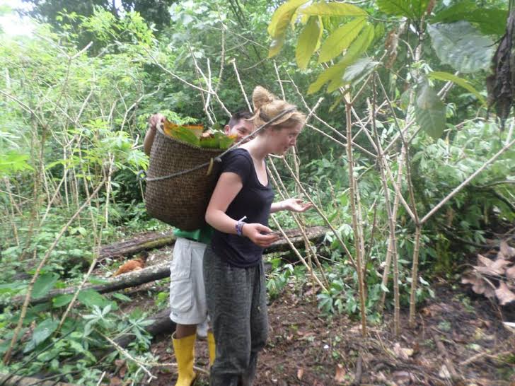 A volunteer helping on the farm carrying a basket of produce on her head.