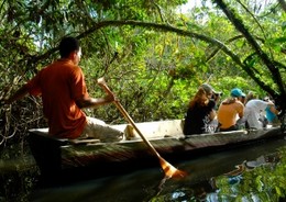 A group of travellers experiencing a tour of the Amazon river in a traditional carved canoe.