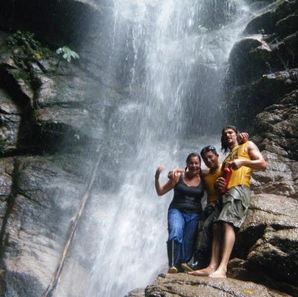 Three people standing by a waterfall in the Amazon jungle.